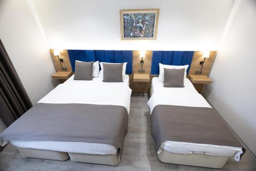 two beds in a small room with blue curtains at Ottoman Palace Hotel Edirne in Edirne