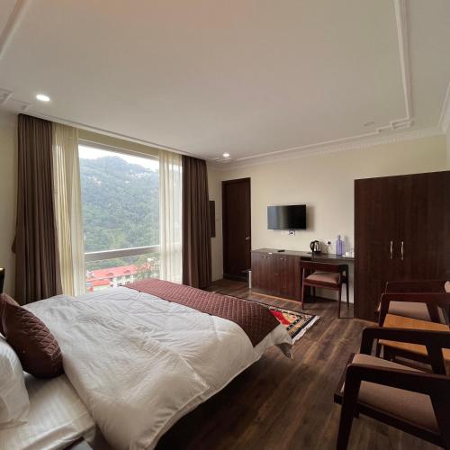 Un dormitorio con una cama grande y una ventana grande. en The Ethenzong, en Gangtok