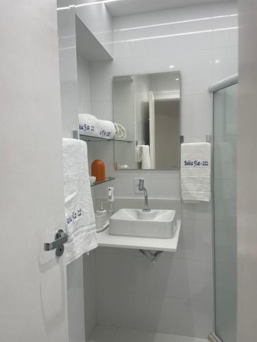 a white bathroom with a sink and a mirror at BAHIA FLAT Apt 222 in Salvador