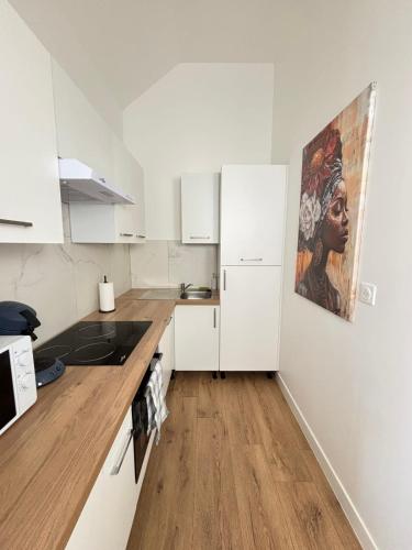 a kitchen with white cabinets and a painting on the wall at Soh Rent Appartment 3 Schiltigheim TV Wifi in Schiltigheim