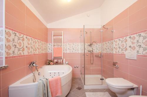 a pink bathroom with a tub and a toilet at Apartments Bellistra Labin in Labin