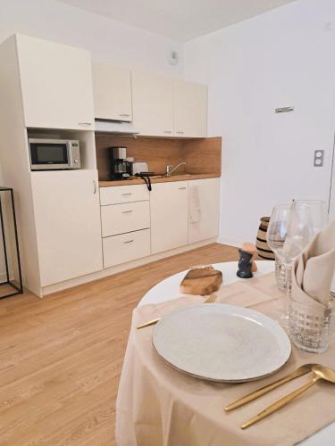 - une cuisine blanche avec une table et une plaque de cuisson dans l'établissement Résidence d'Agen, à Agen