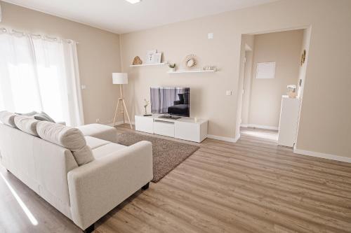 a living room with a white couch and a television at Casa Foros de Amora in Amora