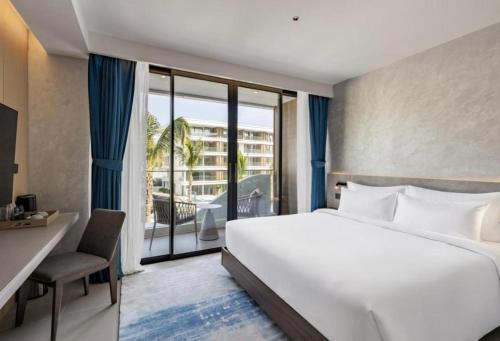 a hotel room with a large bed and a balcony at Sunshine Beach Residence Resort in Phuket Town