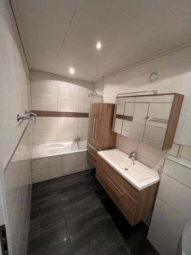 a bathroom with a sink and a tub and a mirror at Schöne Maisonette 4 Zimmer mit Garten in Rodgau