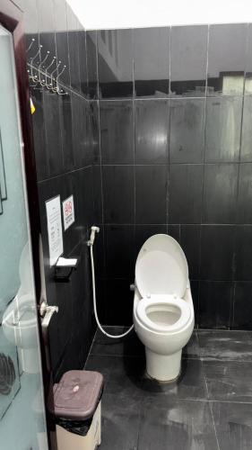 a bathroom with a toilet in a black tiled wall at Zzz Hostel Malang in Malang