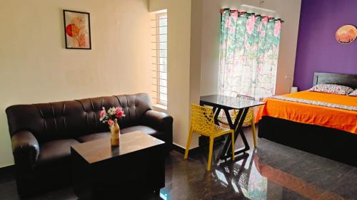 a bedroom with a couch and a bed and a table at Samuels Comfort Homes in Bengaluru