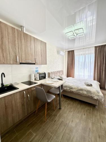 a bedroom with a bed and a table and a kitchen at Апартаменты возле метро НАУЧНАЯ in Kharkiv