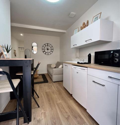 d'une cuisine et d'un salon avec des placards blancs et une table. dans l'établissement Le Paisible Studio, à Montauban