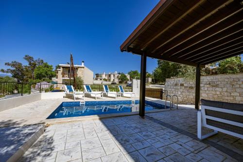 a swimming pool with chairs and a pavilion at Stroumpi Private Pool Villa in Stroumbi