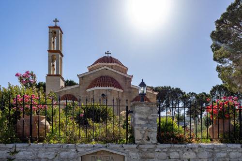 a church with a clock tower behind a fence at Stroumpi Private Pool Villa in Stroumbi