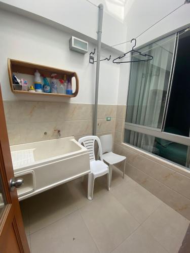 a bathroom with a tub and a chair and a sink at Ravenala - Apartment Paracas in Paracas