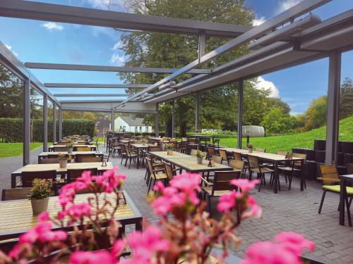 a patio with tables and chairs and pink flowers at Best Western Plus Parkhotel Velbert in Velbert