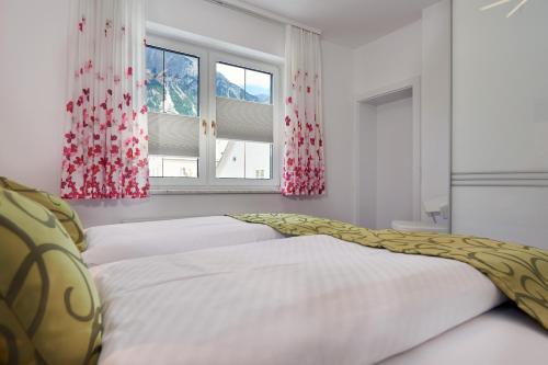 a bedroom with two beds and two windows at Gästehaus Herma in Ramsau am Dachstein