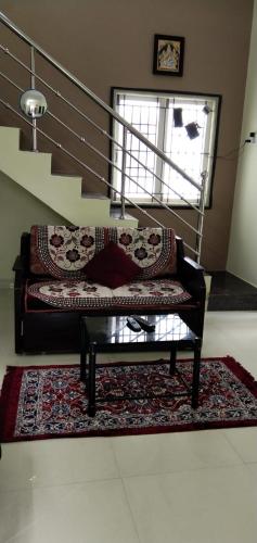 a couch with pillows on a rug in front of a staircase at Anugrahaa Homestay in Tiruchchirāppalli