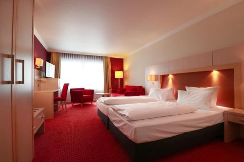 a hotel room with two beds and a red carpet at Hotel Haverkamp in Bremerhaven