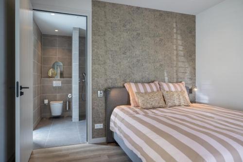 a bedroom with a bed and a bathroom with a shower at Luxe villa aan golfbaan en bosrand in Appelscha in Appelscha