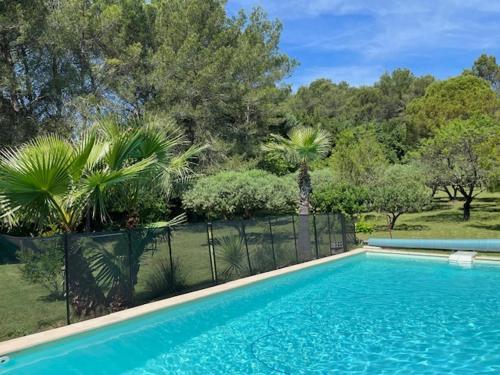 a swimming pool in a yard with a fence and trees at Le gîte du mas in Bagard