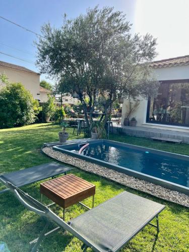 une cour avec une piscine, une table et un banc dans l'établissement villa dans un écrin de verdure, à Saint-Quentin-la-Poterie