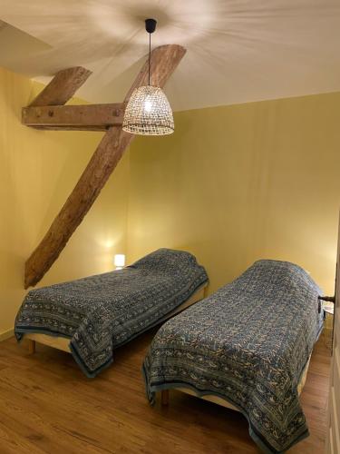 une chambre avec deux lits et un lustre dans l'établissement Gîte de charme dans le Sancerrois, à Bannay