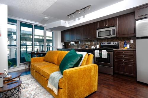a living room with a yellow couch and a kitchen at Downtown Cozy 1BR Condo- Steps from Lake & King street in Toronto