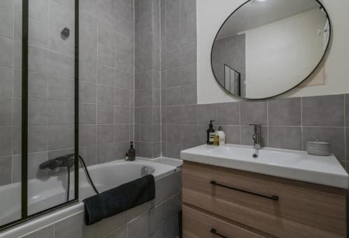 une salle de bain avec une baignoire, un lavabo et un miroir dans l'établissement Appartement parisien baigné de soleil, à Paris