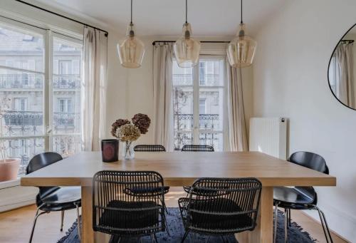une salle à manger avec une table et des chaises en bois dans l'établissement Appartement parisien baigné de soleil, à Paris