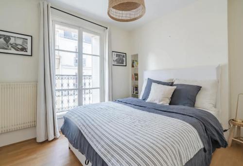 une chambre avec un lit et une grande fenêtre dans l'établissement Appartement parisien baigné de soleil, à Paris