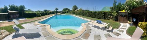 a large swimming pool with white chairs at Villa Ondina Versilia in Lido di Camaiore