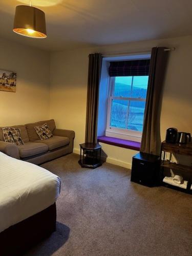 a bedroom with a bed and a couch and a window at New Inn Appletreewick in Appletreewick