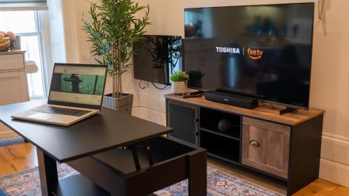 a living room with a television and a laptop on a table at Select SA - Queens Terrace in Reading