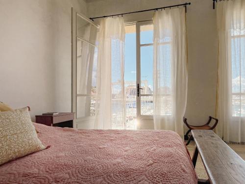 een slaapkamer met een bed en een groot raam bij CASA ABEILLE in La Ciotat