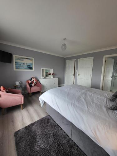 a bedroom with a large bed and two chairs at Ashbury House - Room Only in Keel