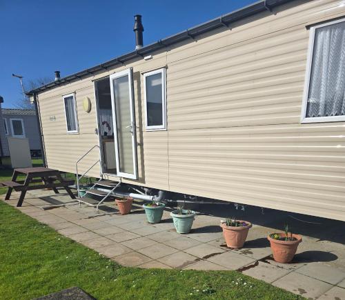a mobile home with potted plants in front of it at Trecco bay birch in Newton