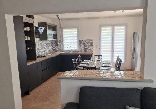 - une cuisine avec une table, des chaises et un comptoir dans l'établissement Les Pins grand duplex T5 avec jardin les plages à pied, à Pornichet