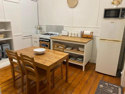a kitchen with a wooden table and a refrigerator at Canterbury Cottage - dog friendly - fully fenced in Wonthaggi