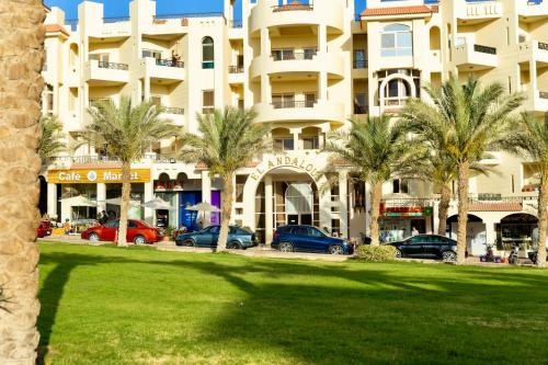 a large building with palm trees in front of it at El Andalous Sea View Apartment Sahl Hasheesh in Hurghada