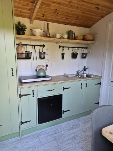 a kitchen with white cabinets and a sink at Clissmann Farm Shepherds Hut in Rathdrum