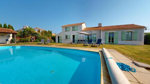une grande piscine bleue devant une maison dans l'établissement Villa Emeraude - Golf & Plage, à LʼAiguillon-sur-Vie