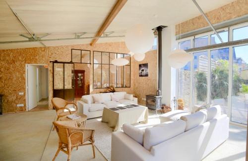 ein Wohnzimmer mit weißen Möbeln und großen Fenstern in der Unterkunft Le Loft du Pré - Maison d'architecte - Le Mans in Le Mans