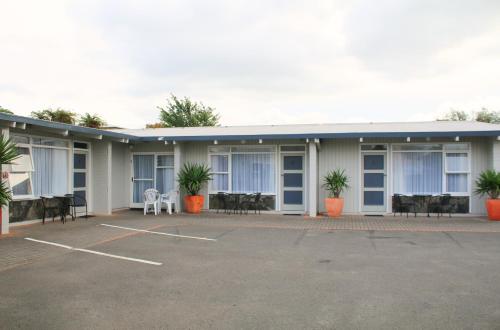 a building with tables and chairs in a parking lot at Fernleaf Motel in Rotorua