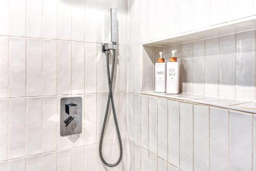 a shower in a white tiled bathroom with a hose at Sauna Bain Nordique Cinéma Vue Montange in Chamonix-Mont-Blanc