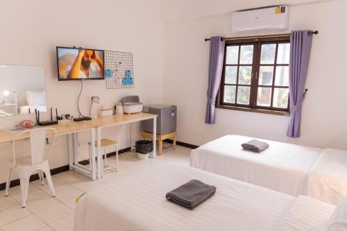 a room with two beds and a desk with a computer at Jida Place in Chiang Mai
