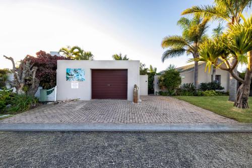 a garage door on a white house with palm trees at Pelican Palms Aston Jeffreys Bay in Jeffreys Bay