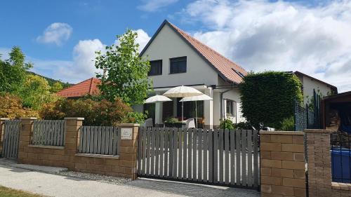 a white house with a fence and an umbrella at Relax Balaton Apartmanok in Balatonfüred