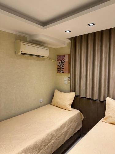 a small room with two beds and a window at Temple & Nile view in Luxor
