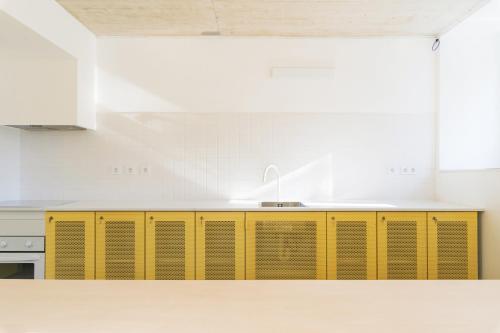 a kitchen with yellow cabinets and a sink at StudentVille Palmeiras in Lisbon