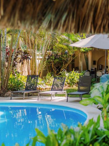 a swimming pool with two chairs and an umbrella at Casa Real Sayulita Hotel Boutique in Sayulita