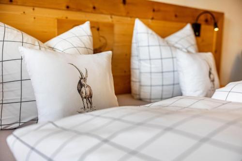 a bed with white pillows with a bird on it at Ferienwohnung Nordic -Reit im Winkl in Reit im Winkl