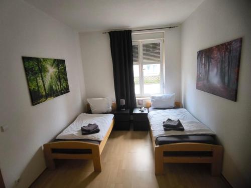 two twin beds in a room with a window at Preiswerte Apartments für Monteure, WLAN, Smart-TV & kostenfreie Parkplätze in Neupetershain